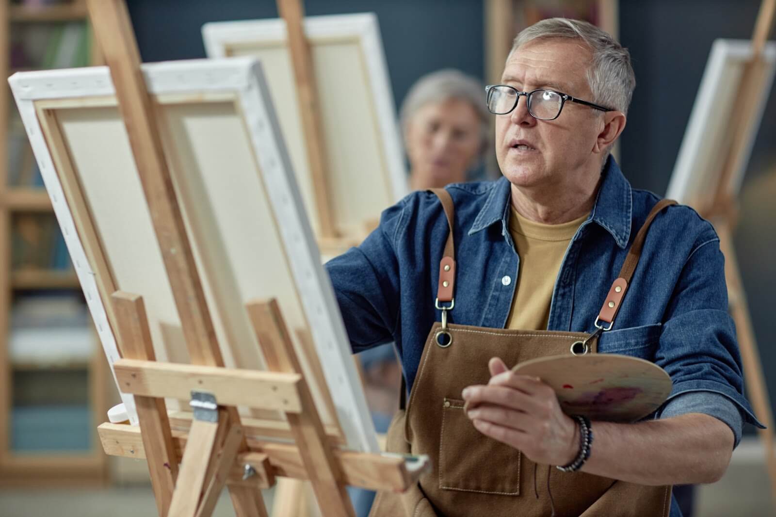 Mature man painting on a canvas with a concentrated expression.
