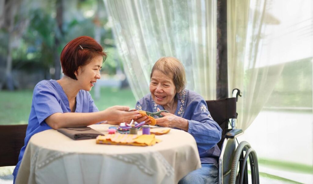 Older adult and her caregiver crafting together.