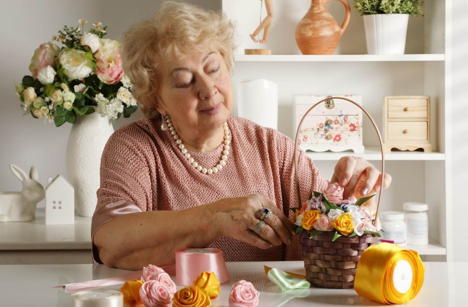 An older adult joyfully making nature-inspired crafts in a community space.