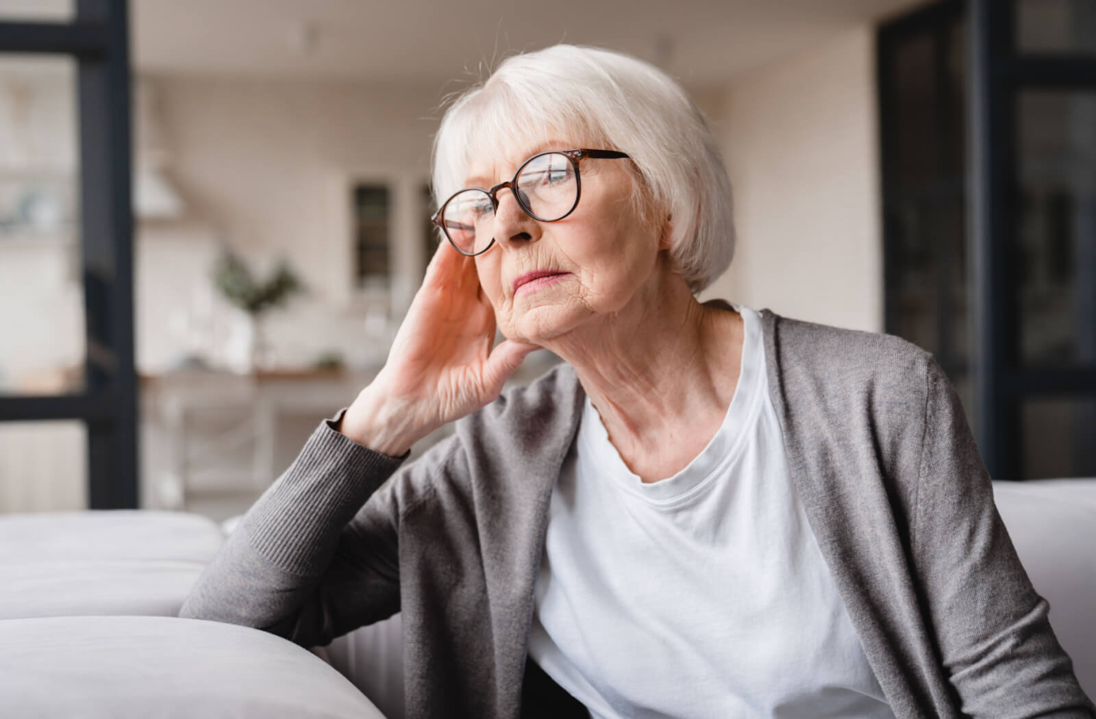 A lonely-looking senior woman staring blankly at a distance.