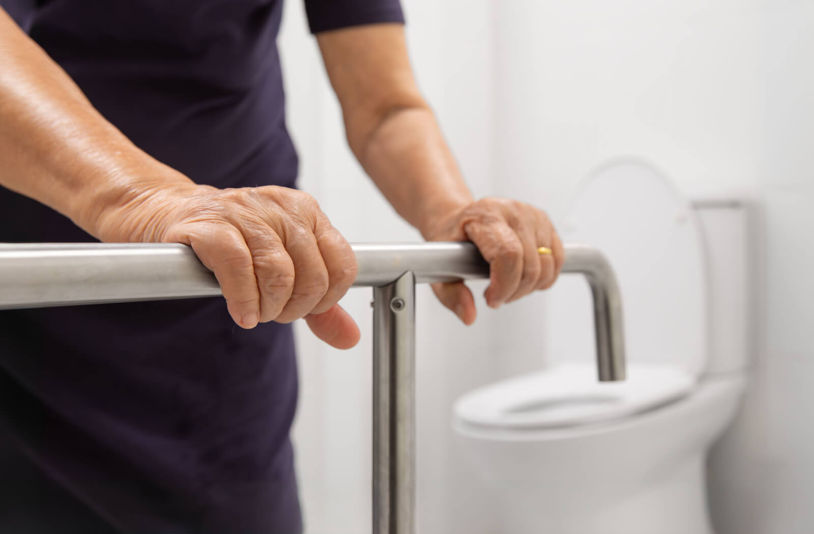 A caregiver testing a grab bar in a bathroom to make sure the room is safe for someone with dementia.