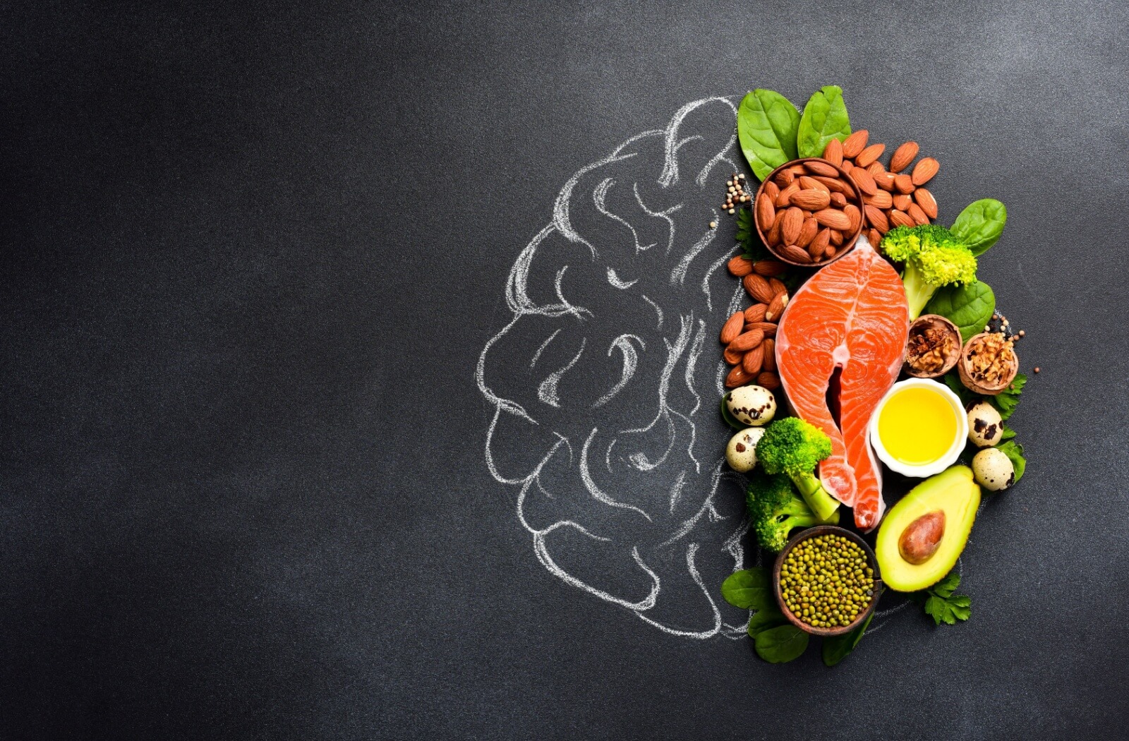 On a chalkboard, one half of a brain is drawn in chalk, the other half composed of brain-healthy foods like fish and nuts