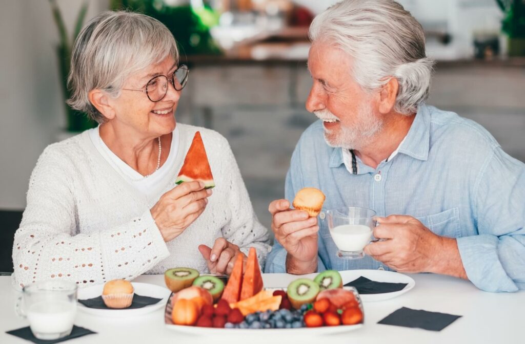 An older adult couple sit at a table, sharing an afternoon snack full of berries to support their brain health